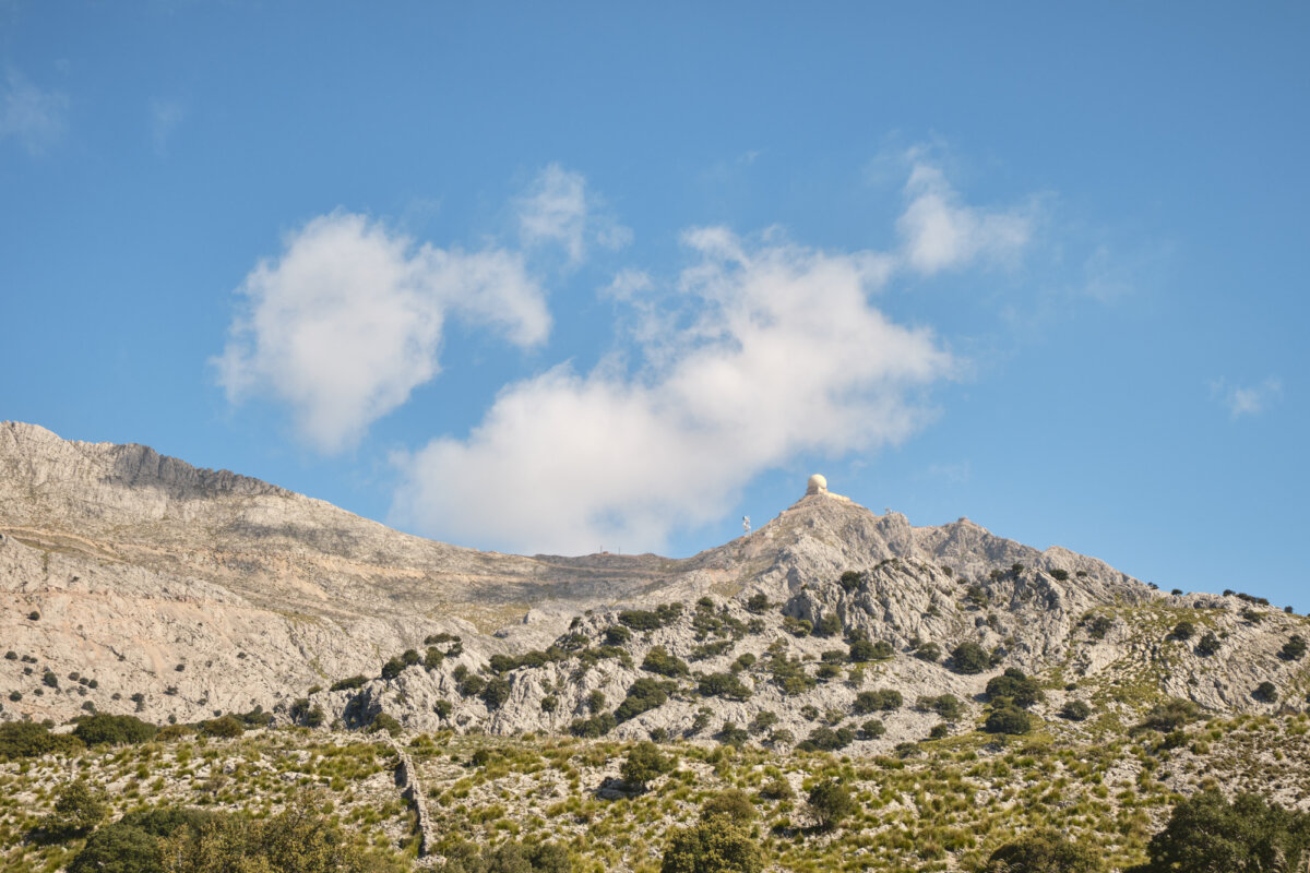 Kahler Berg mit Radarkuppel am Gipfel unter blauem Himmel, vereinzelt Wolken.