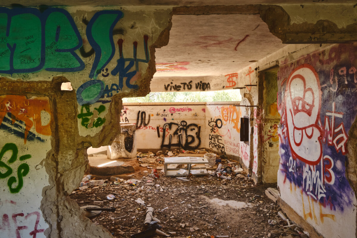Verlassenes Gebäude mit bunten Graffitis an den Wänden und Schutt auf dem Boden.
