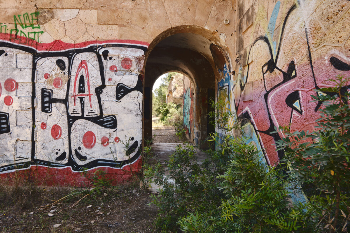 Verlassener Tunnel mit farbigem Graffiti und Pflanzen an den Wänden in einer Ruine.