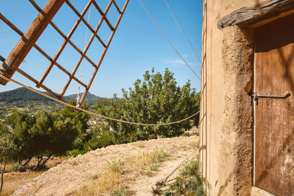Ansicht einer rustikalen Windmühle mit Landschaft im Hintergrund unter klarem Himmel.